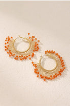 Solburst wire-wrapped beaded sunburst hoop earrings in the Tangerine variant on a warm beige background