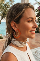 Model wearing solburst wire-wrapped beaded sunburst hoop earrings in the Tangerine variant, view 3