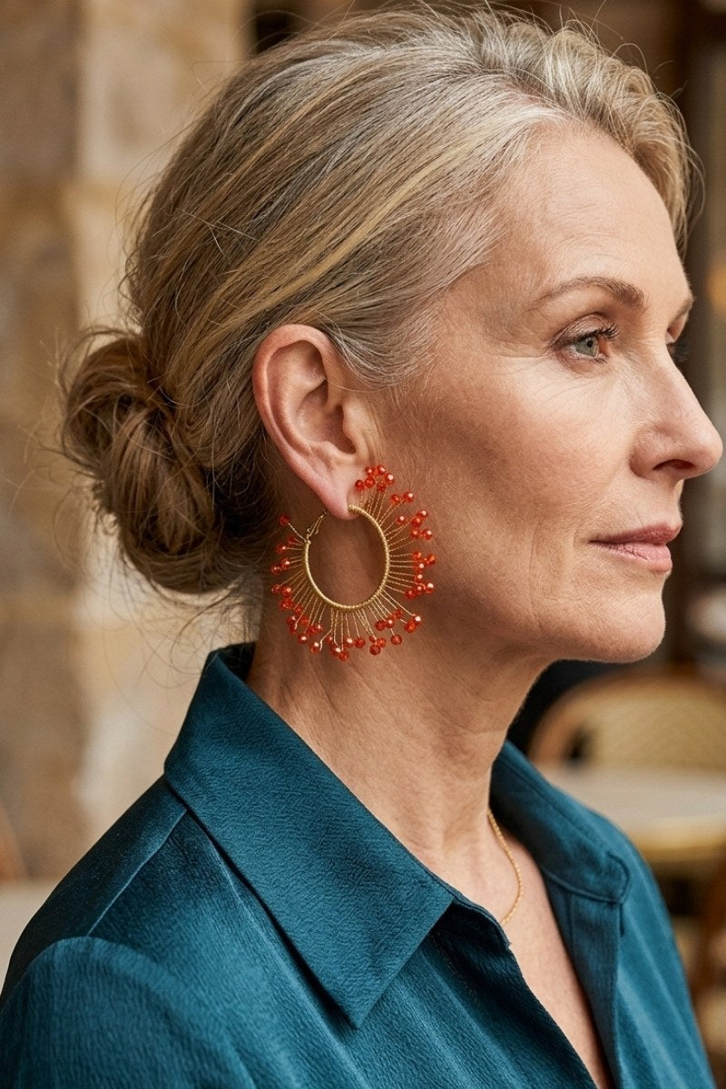 Model wearing solburst wire-wrapped beaded sunburst hoop earrings in the Tangerine variant, view 1